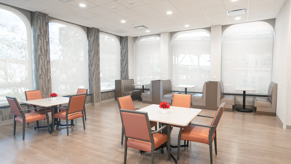 A modern dining area with tables and chairs, featuring ample natural lighting.