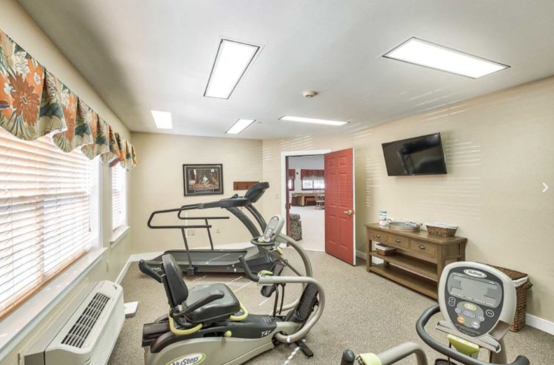A well-equipped fitness room featuring a treadmill, stationary bike, and television.
