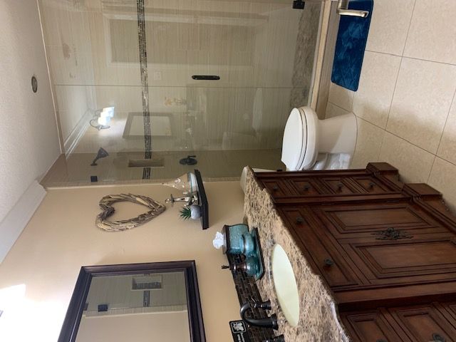 A modern bathroom with a glass shower, wooden vanity, and decorative elements.