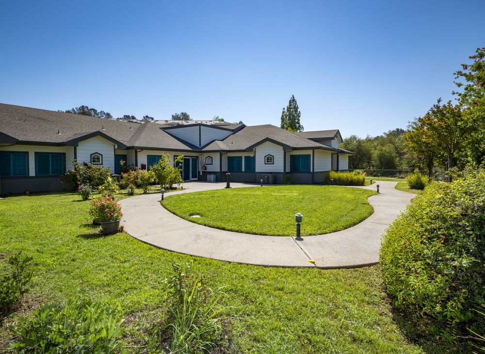A spacious residential home with a well-maintained lawn and circular driveway.
