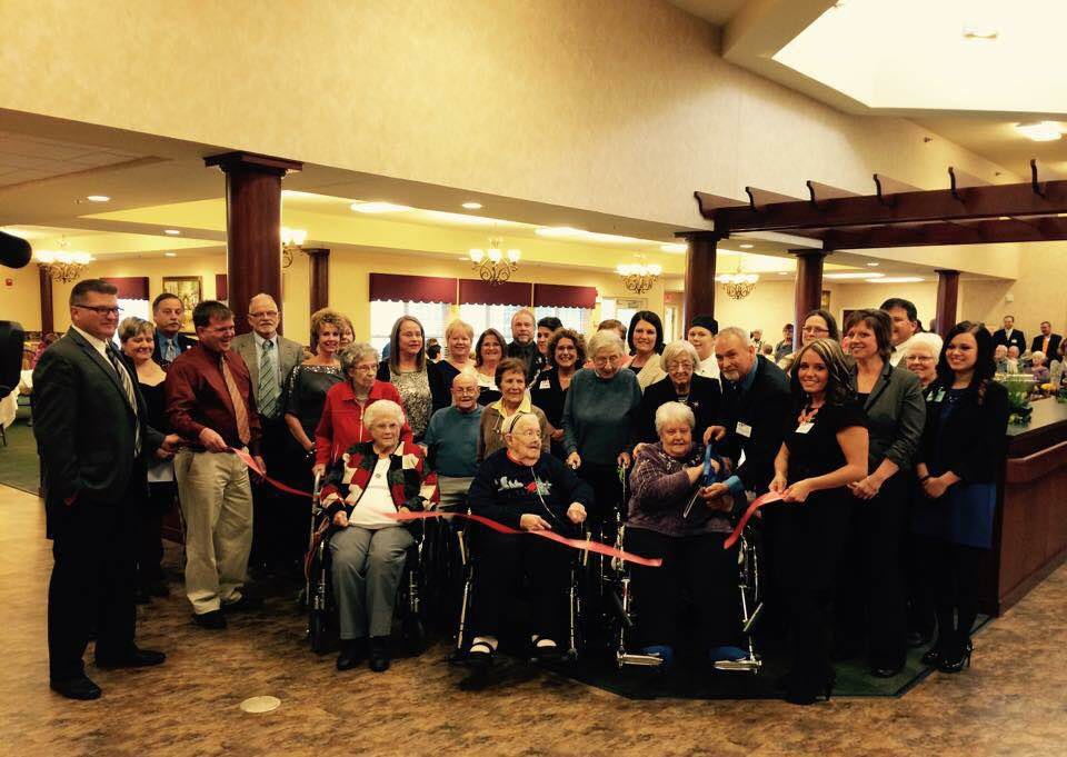 A group of people gathered for a ribbon-cutting ceremony indoors.