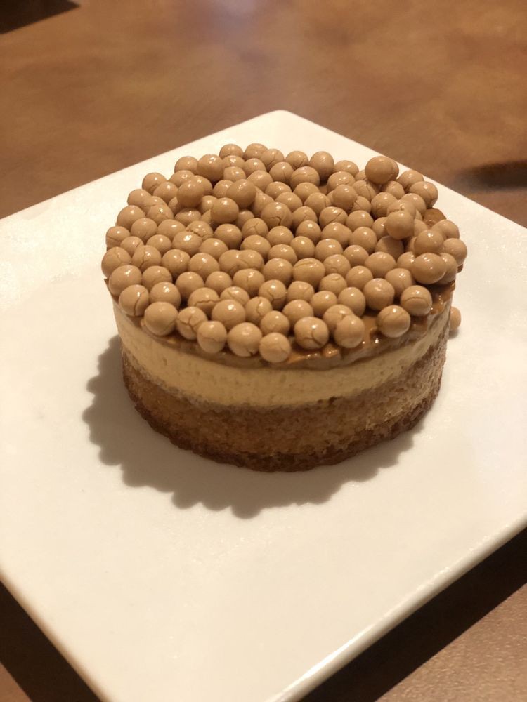 A beautifully presented layered dessert topped with small round decorations.
