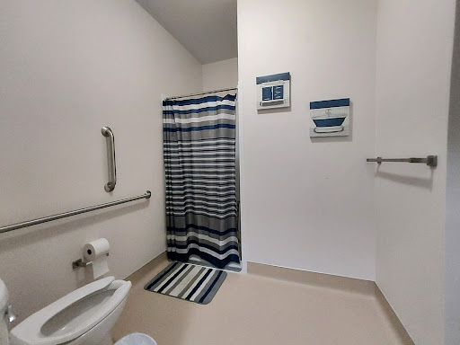 A spacious and modern bathroom featuring a striped shower curtain, matching bath mat, and accessibility features.