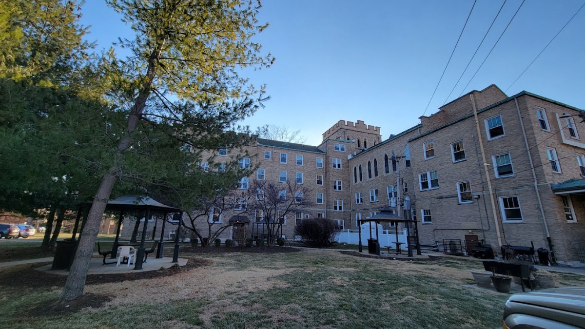 A residential area featuring a playground surrounded by apartment buildings and trees.