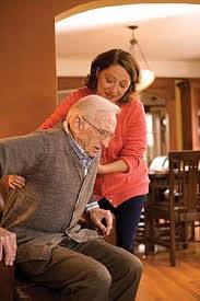 A caregiver assisting an elderly person with standing up.