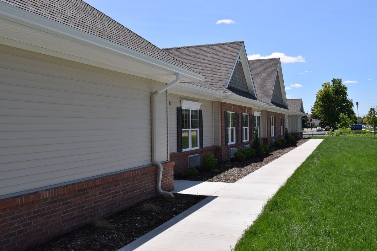 A suburban residential building with a sidewalk and neatly maintained lawn.
