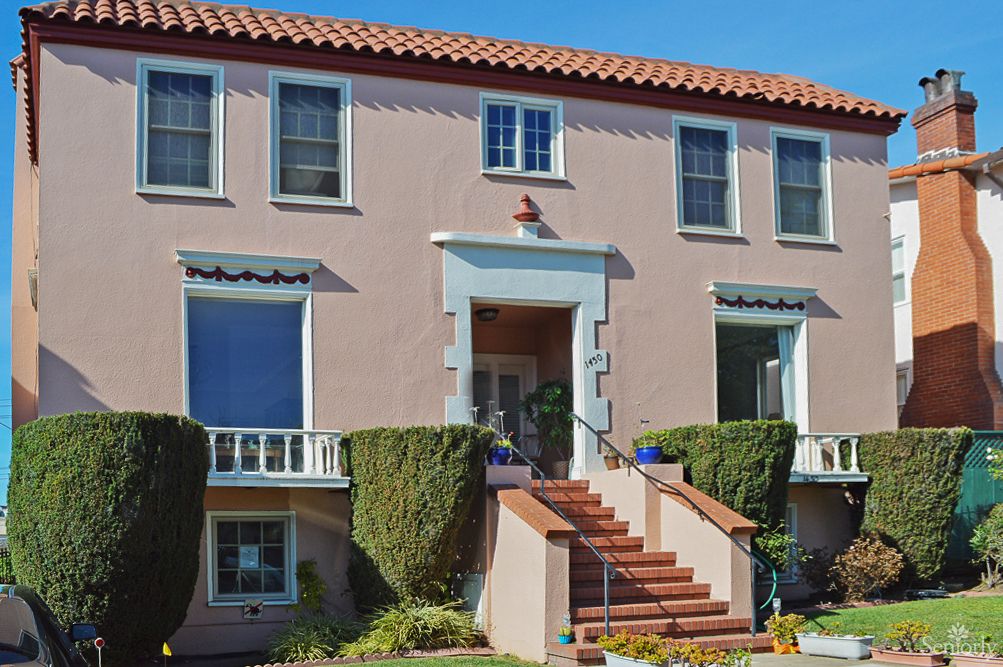 A two-story residential house with a tiled roof and manicured shrubs lining the entrance steps.