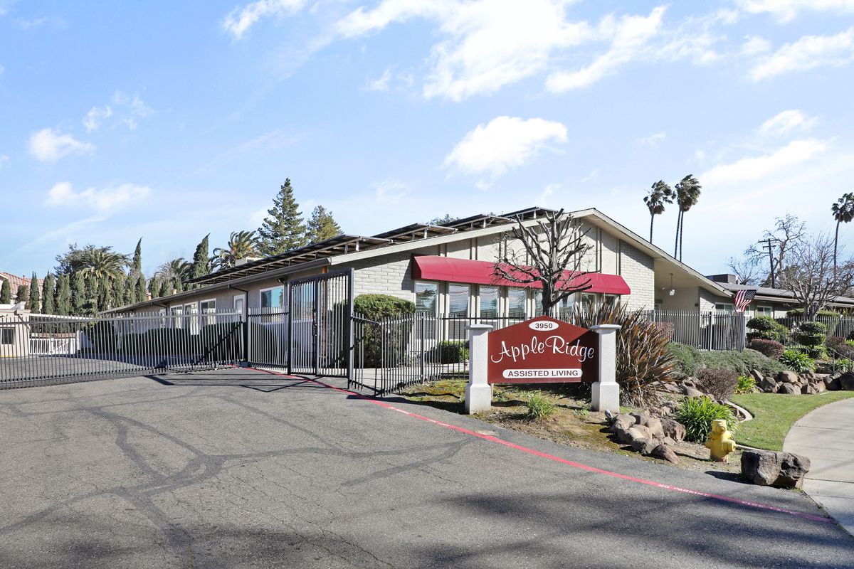 A roadside motel with a red awning and sign, surrounded by trees.