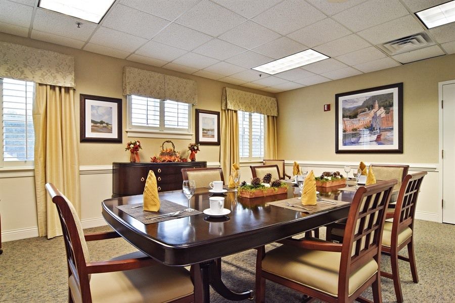 An elegantly decorated dining room featuring a large table set for meals, surrounded by chairs and adorned with artwork on the walls.