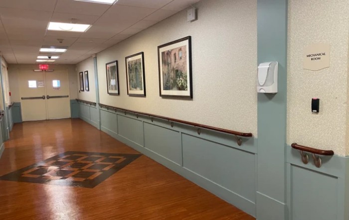 A hallway with framed artwork on the walls and a wooden floor.