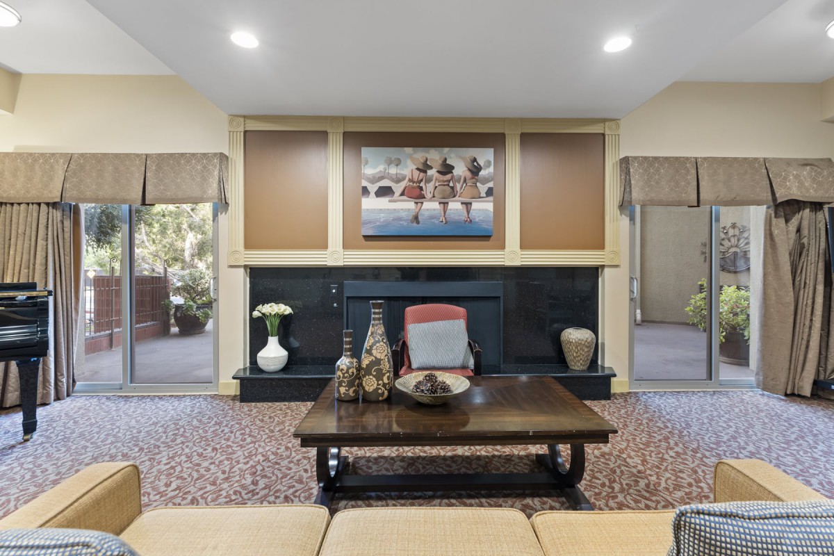 A cozy living room featuring a central fireplace, decorative items on a coffee table, and artwork displayed above.
