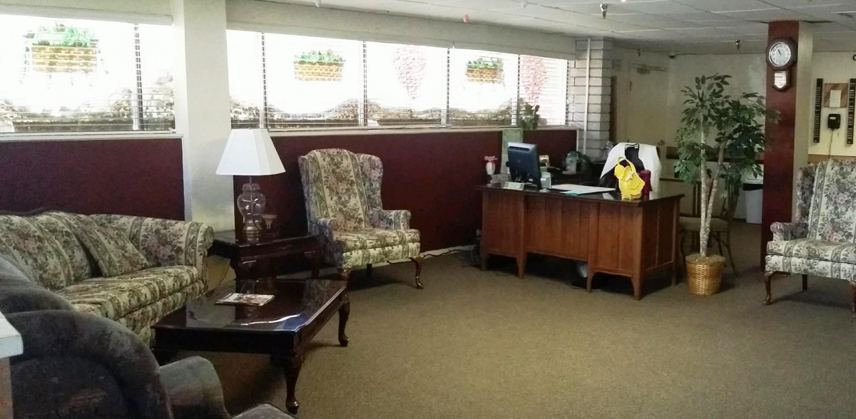 A quiet office lobby with a desk and floral armchair.