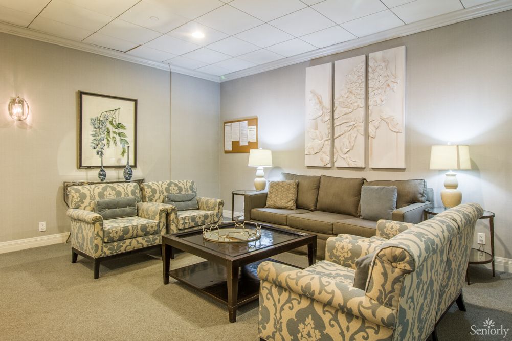 A cozy living room with patterned armchairs, a sofa, and decorative wall art.