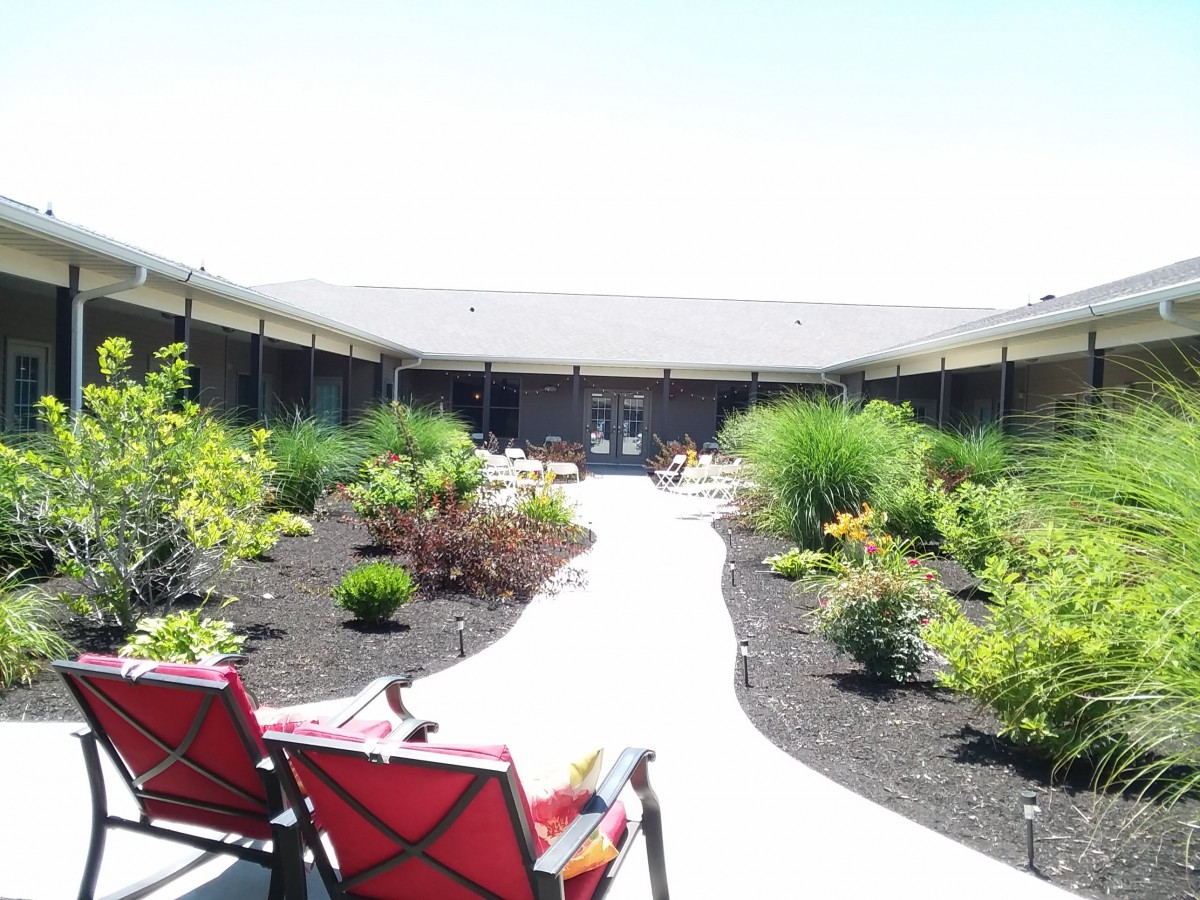 A beautifully landscaped courtyard with a pathway and red chairs.