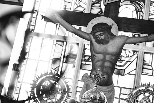 A striking black and white depiction of the crucifixion, showcasing the figure of Jesus Christ against a backdrop of stained glass.