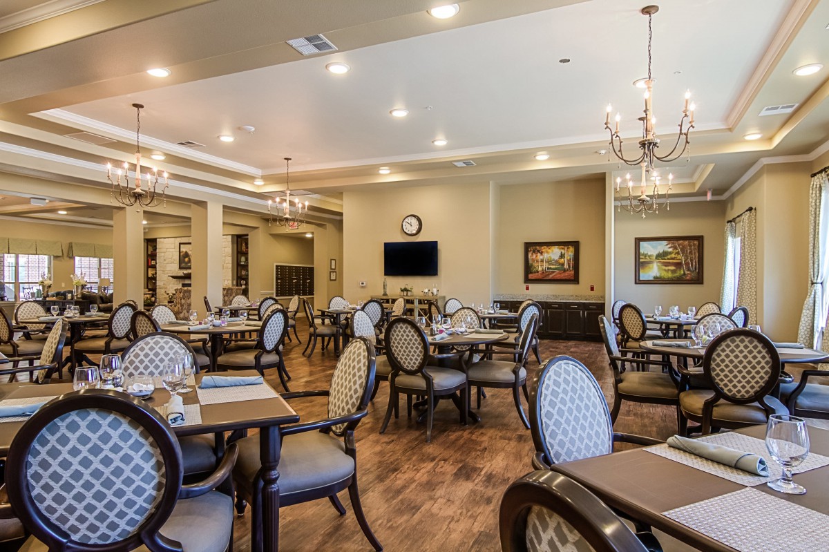 An elegant dining room with chandeliers and neatly arranged tables and chairs.