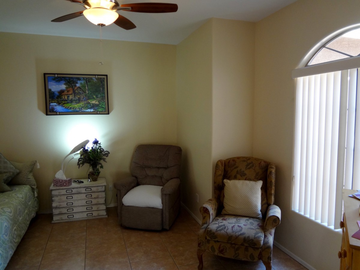 A cozy living room featuring two armchairs, a lamp, and a painting on the wall.