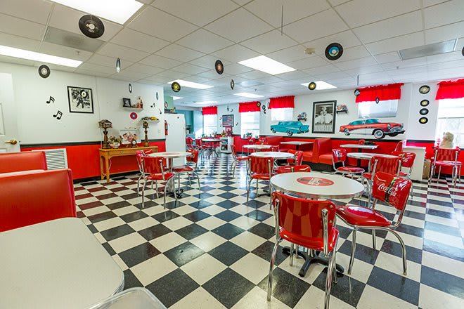 A retro 1950s-style diner with red decor and a checkered floor.