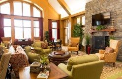 A cozy and modern living room featuring warm tones, comfortable furniture, and a stone fireplace.