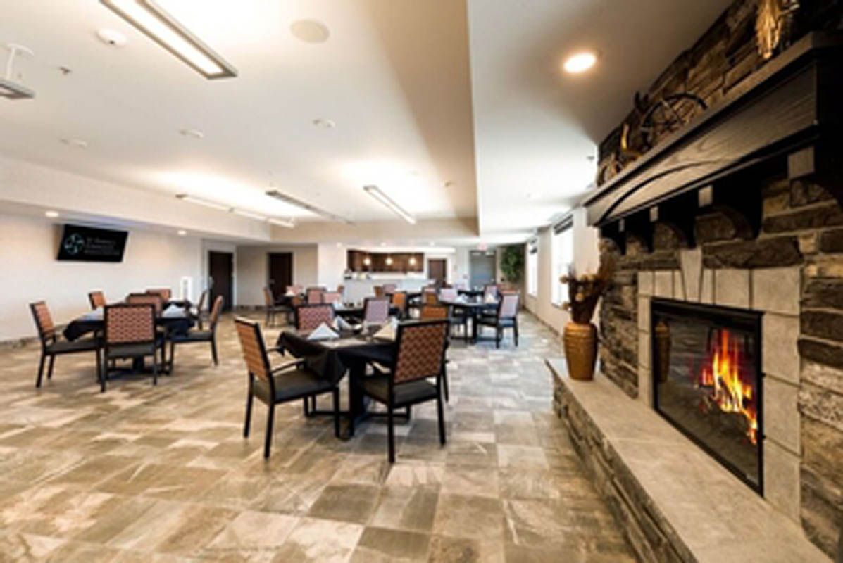 A cozy dining area with a modern interior, featuring multiple tables and a stone fireplace.