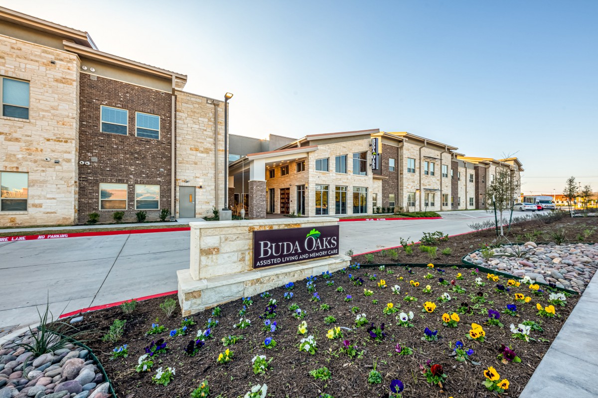 A modern residential building with a landscaped garden and vibrant flowers in the foreground.