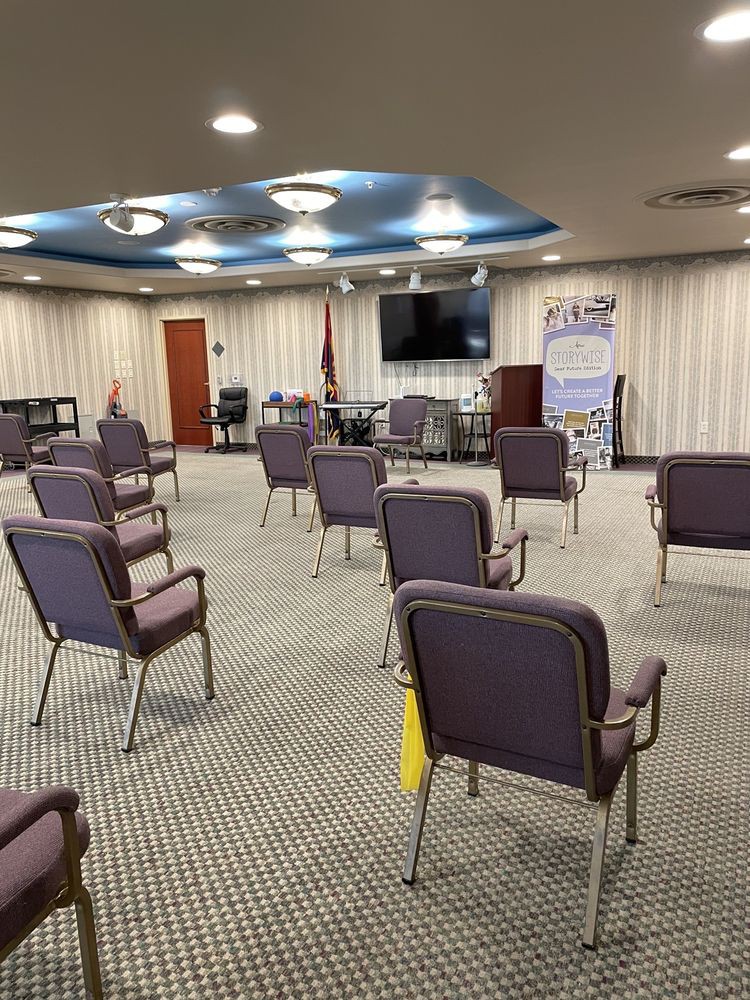 An empty conference room with rows of chairs facing a screen, prepared for a meeting.