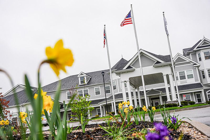 A picturesque building with flags and colorful flowers in the foreground.