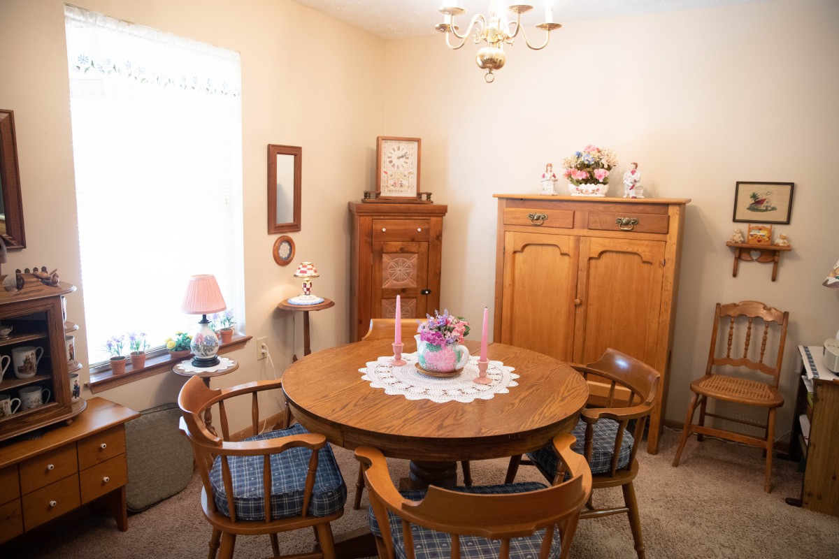 A cozy dining room with a round wooden table and matching chairs, adorned with decorative items and natural light.