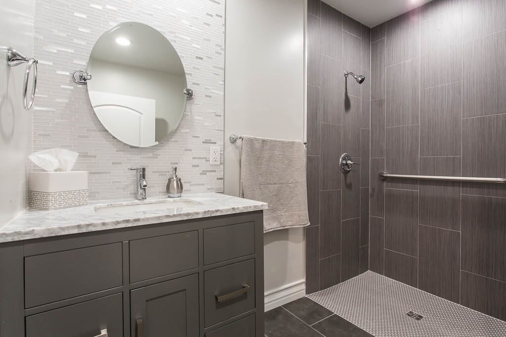 A modern bathroom with a walk-in shower and gray tile design.