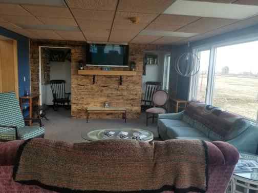 A cozy living room with a brick fireplace, couches, and a television.