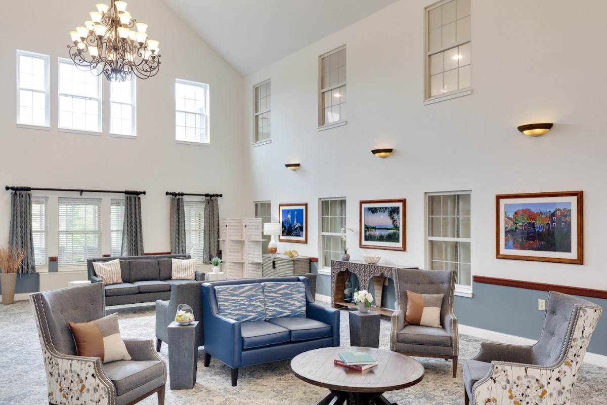 A spacious and elegantly designed living room with high ceilings, featuring modern furniture and a large chandelier.