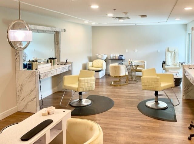 A modern and clean salon interior with styling chairs and mirrors.