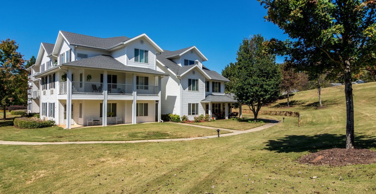 A suburban residential building with a well-maintained lawn and trees.