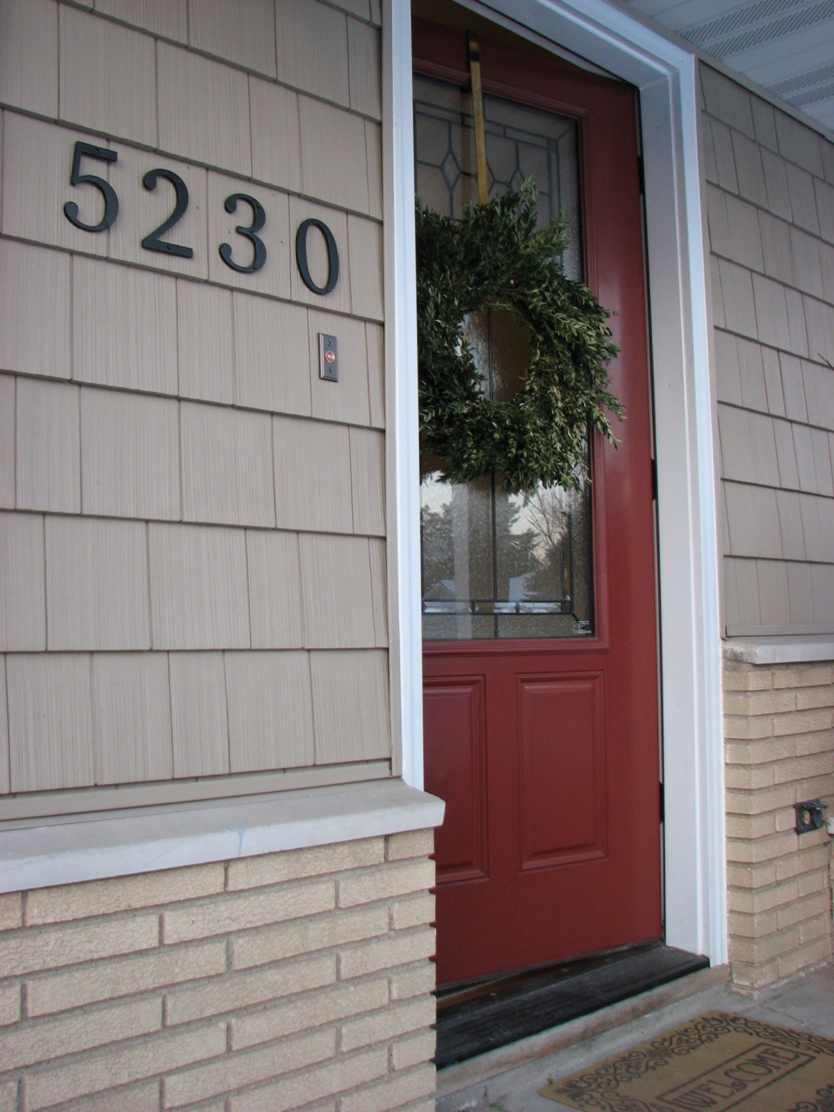 A house with a red door adorned with a wreath and the address number 5230.