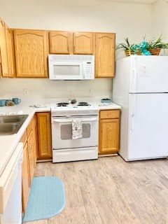 A bright kitchen with wooden cabinets, featuring a stove, microwave, and refrigerator.