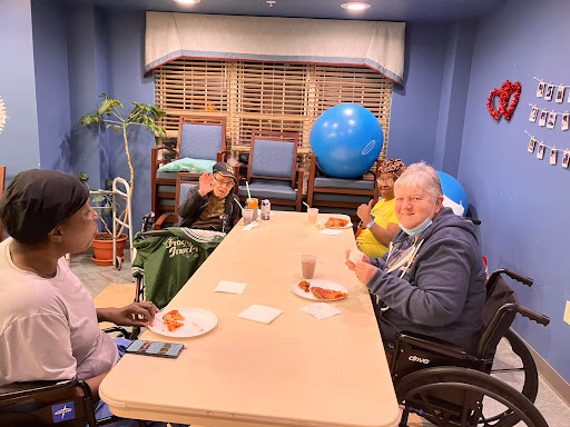 A group of elderly individuals enjoying snacks and conversation in a cozy indoor setting.