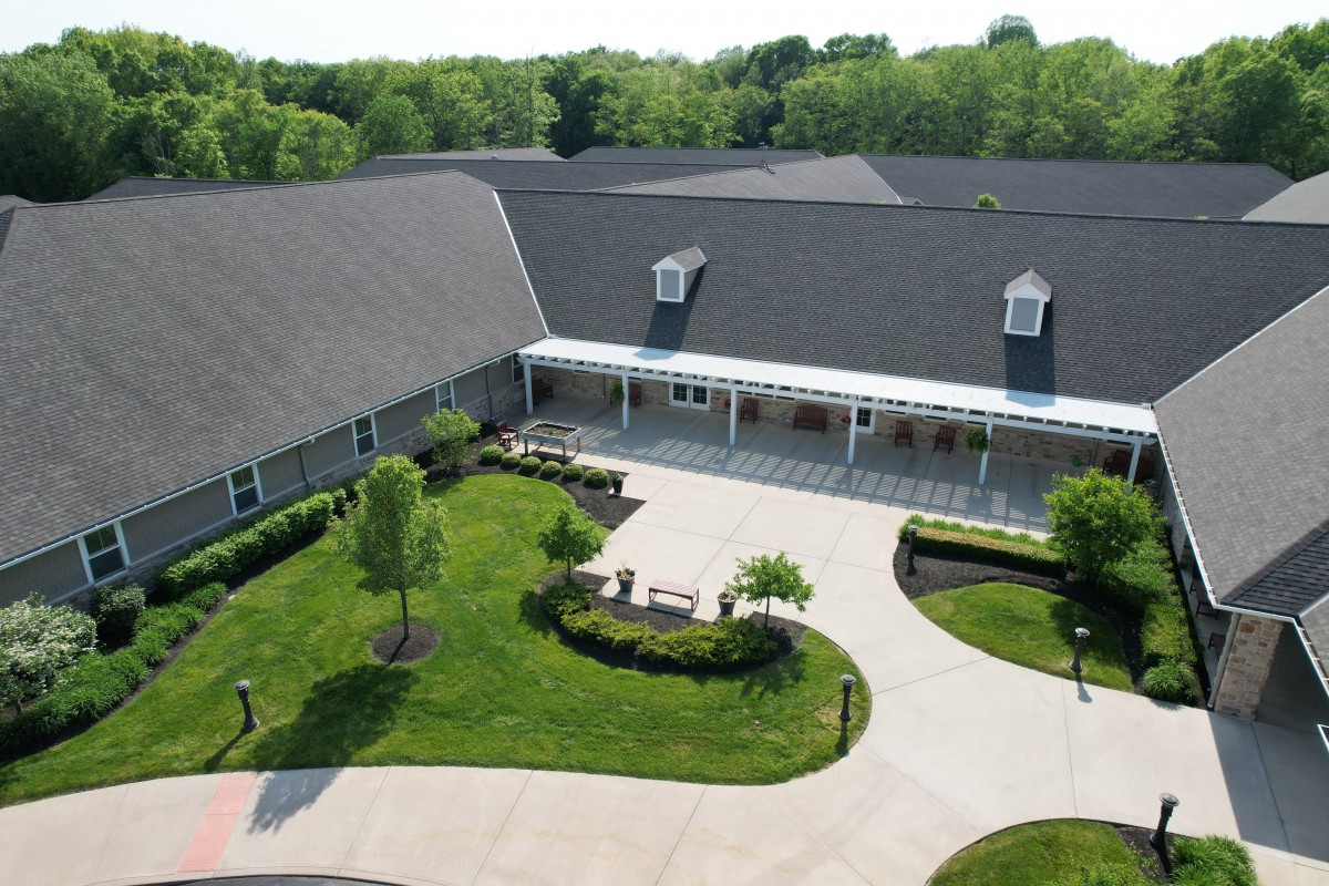 Aerial view of a large building with a landscaped garden and driveway.