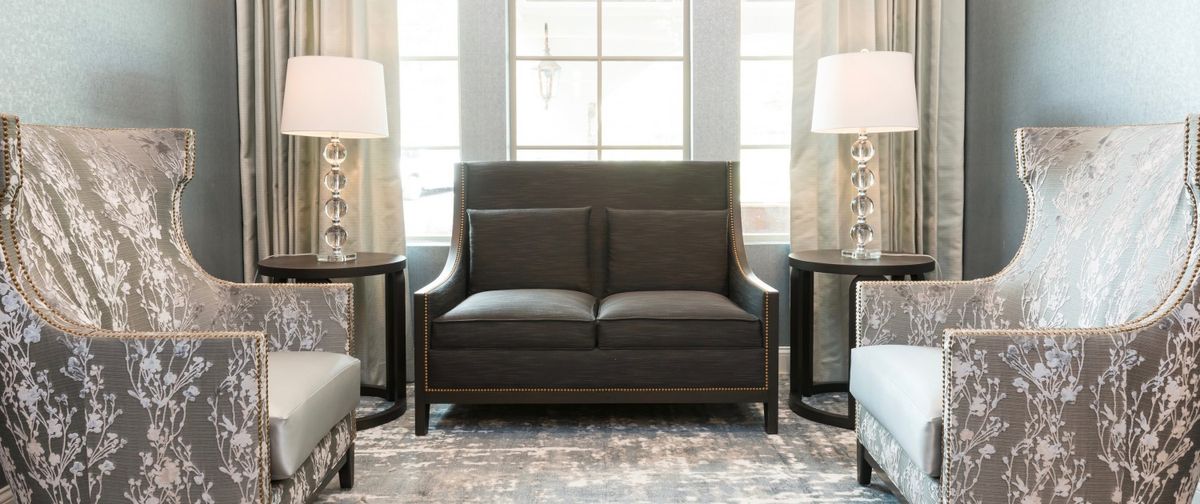 A modern sofa placed in a well-lit living room with two side tables and large windows.