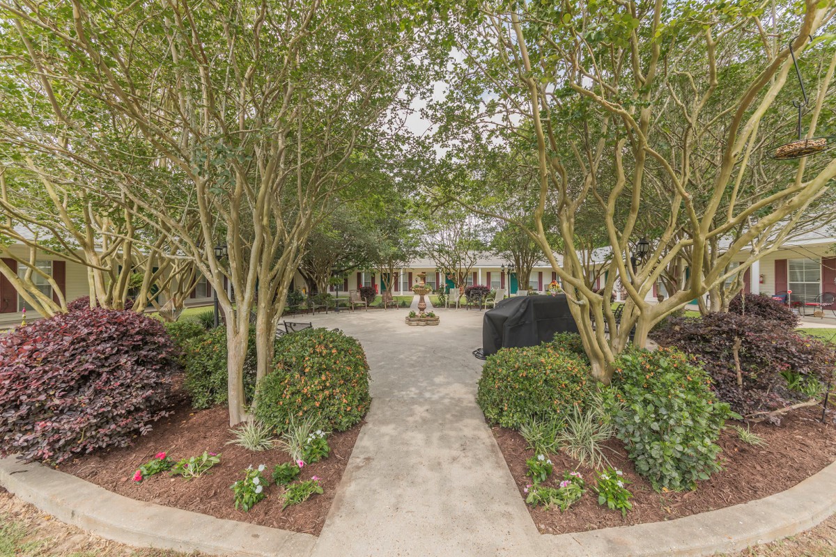 A serene garden pathway surrounded by lush trees and well-maintained landscaping.