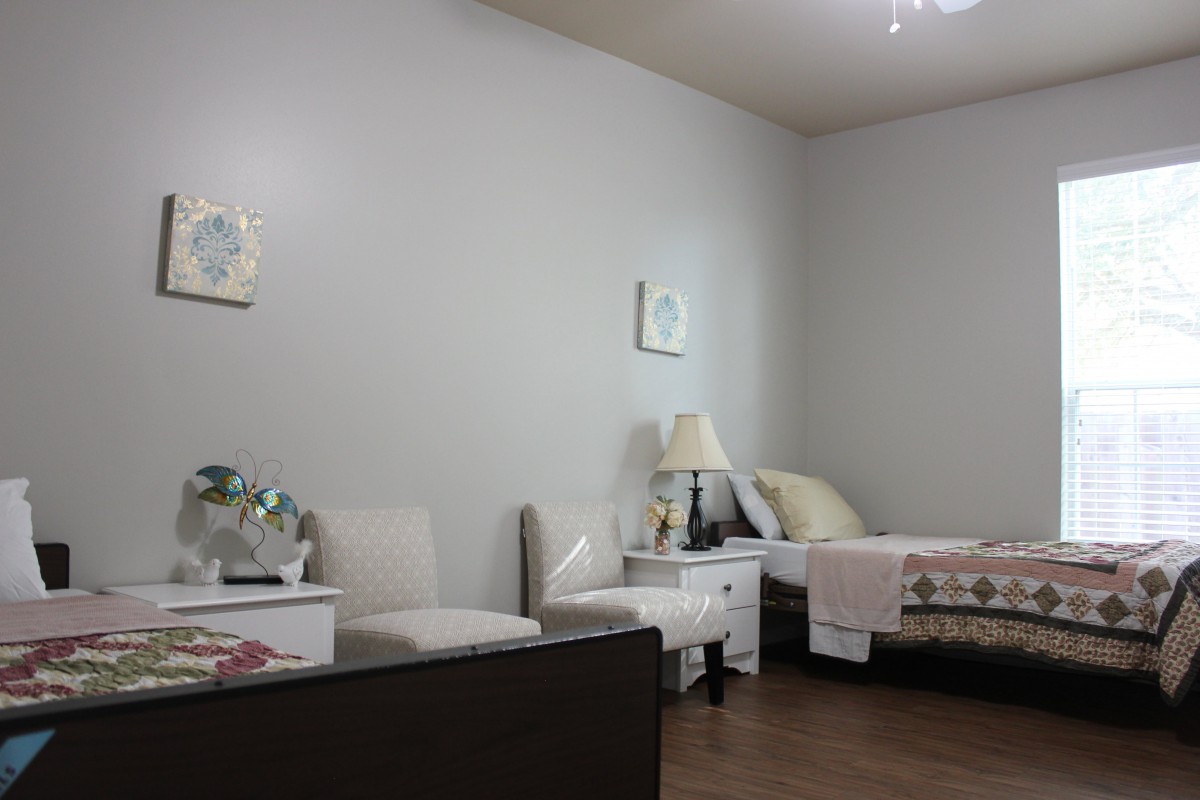 A cozy bedroom with a neatly made bed, nightstand, and comfortable chairs.