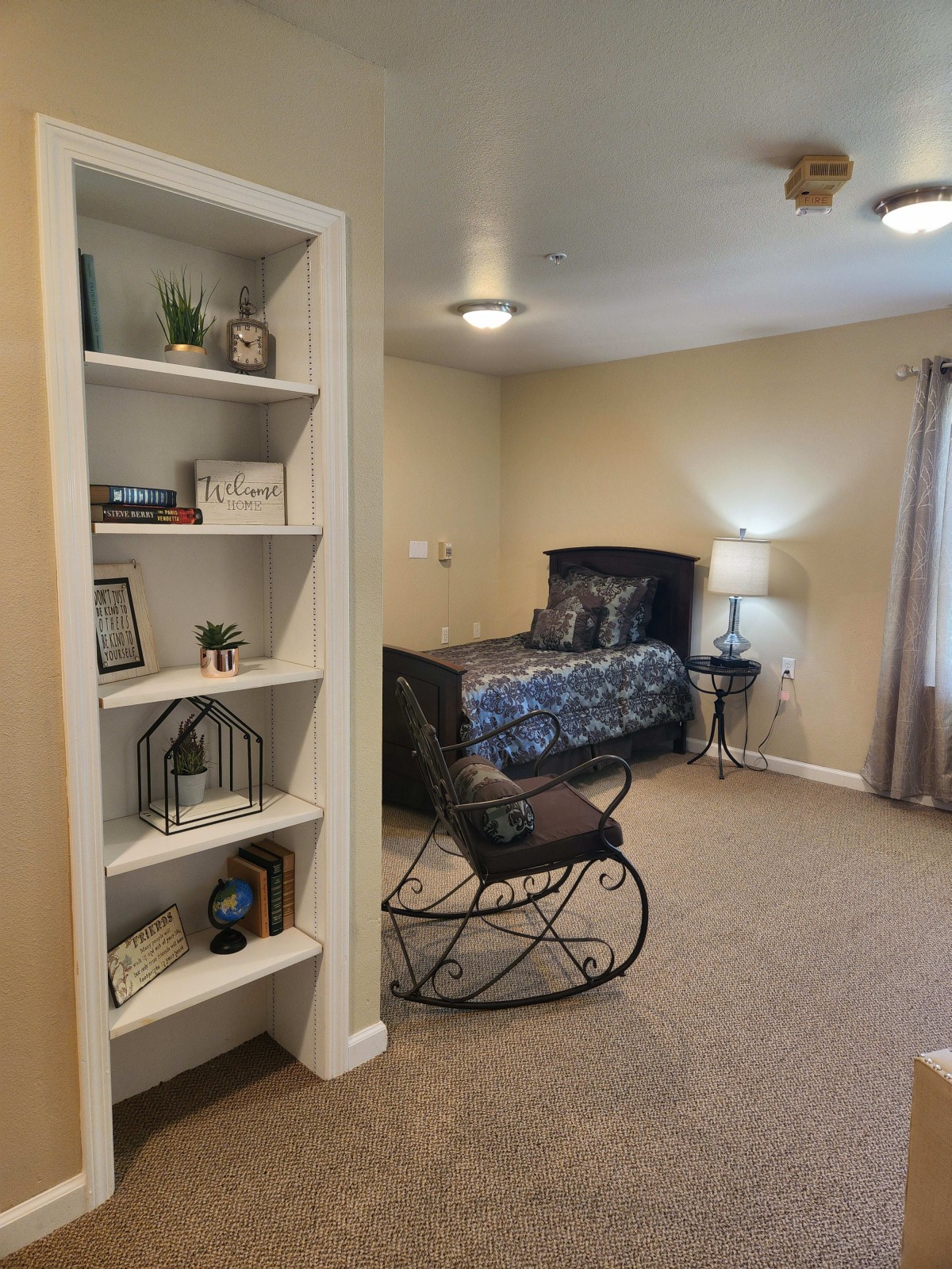 A cozy bedroom with a bookshelf and a rocking chair.