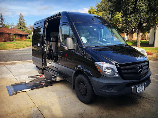A black Mercedes-Benz van equipped with a wheelchair ramp, parked and ready for use.