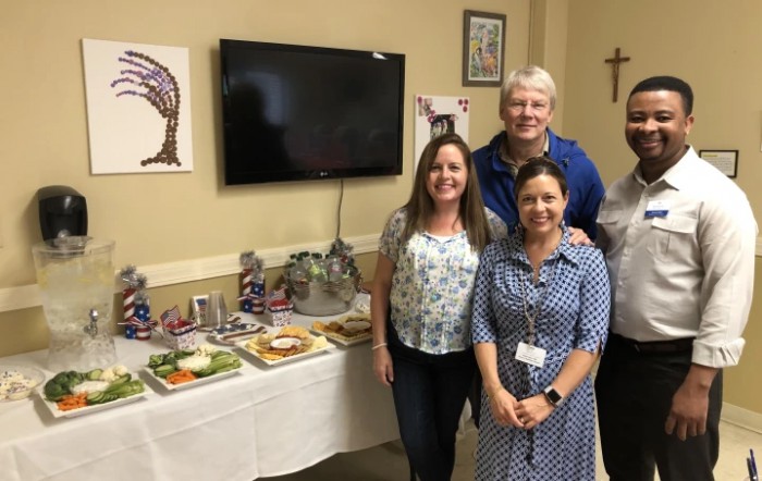 A group of people posing in front of a table with food during a celebration.