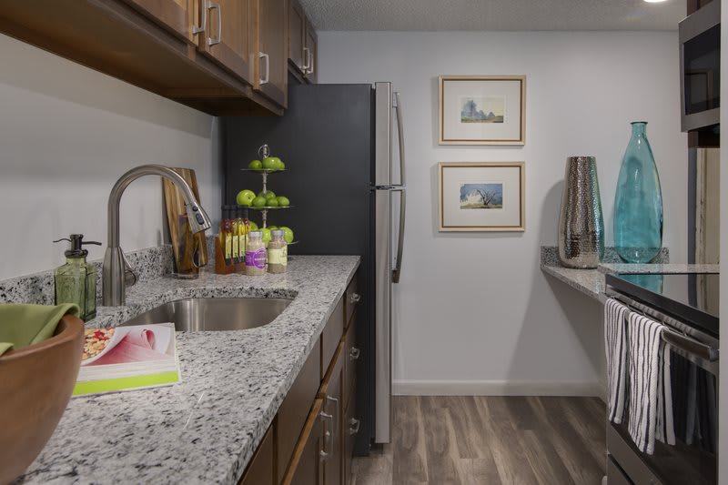A modern kitchen with granite countertops, wooden cabinets, and stainless steel appliances.