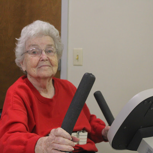 An elderly woman exercising on a stationary bike, promoting health and fitness.