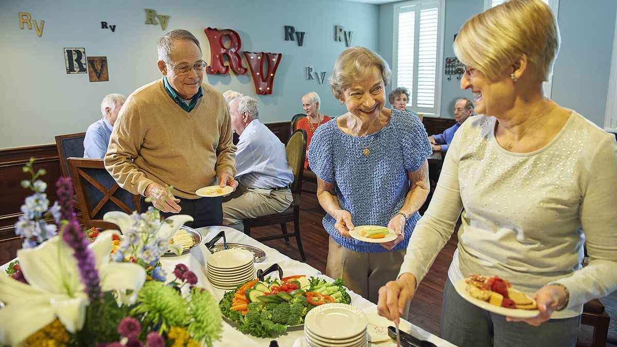Elderly individuals enjoying a buffet-style meal at a social gathering.