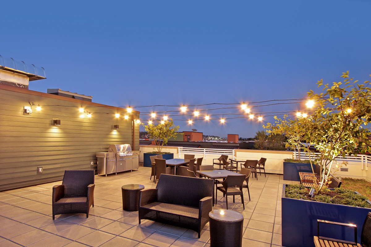 A cozy rooftop patio illuminated by string lights in the evening.