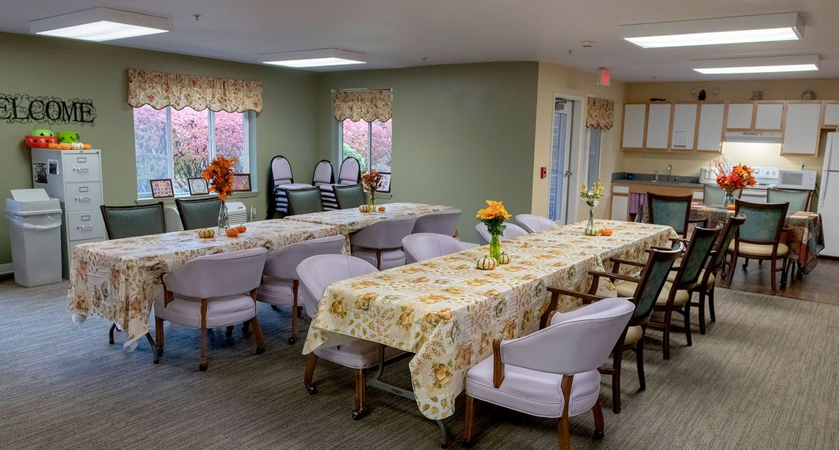 A cozy dining room with tables and chairs, decorated with floral patterns and fresh flowers.