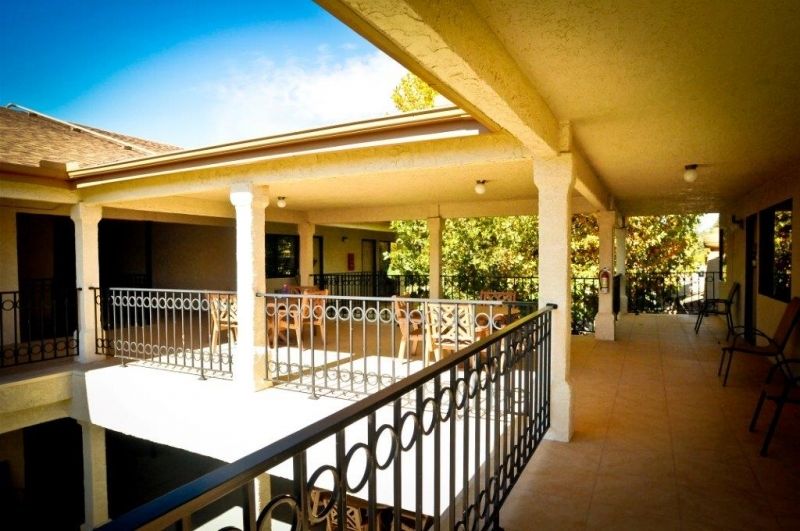 Sunny outdoor balcony with columns and railing.
