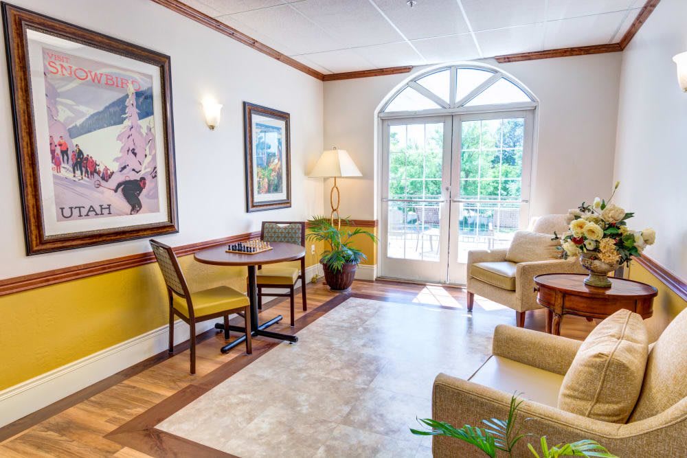 A bright and cozy living room with comfortable seating, large windows, and decorative artwork.